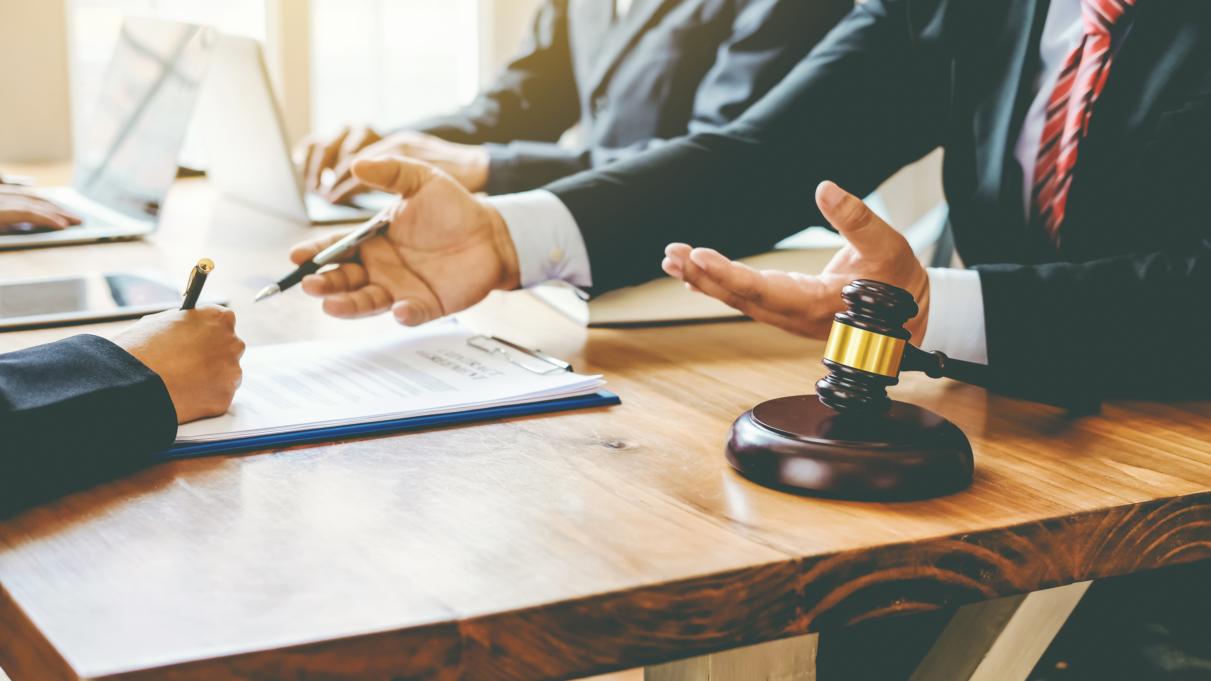 Legal team reviewing a vendor contract with a gavel on the table, representing contract certification and risk reduction in B2B deals
